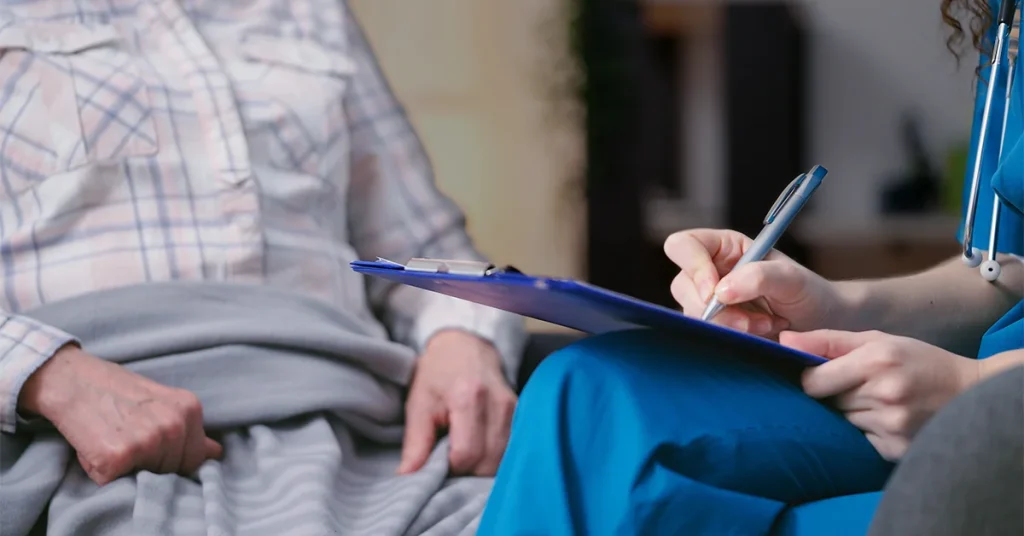 Nurse talking with an elderly patient, filling out private medical forms.