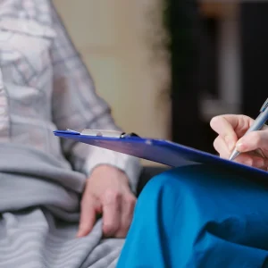 Nurse talking with an elderly patient, filling out private medical forms.