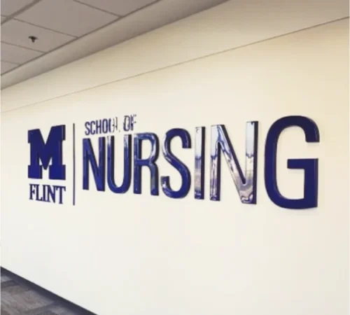 The University of Michigan-Flint School of Nursing sign hanging in a hallway